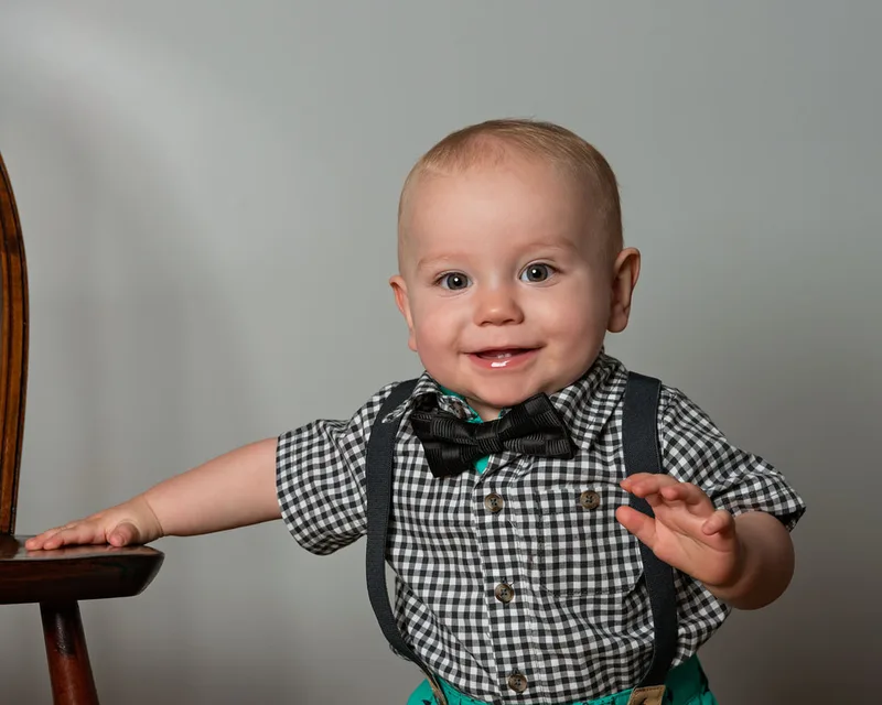 One year old boy first birthday photo smiling in plaid outfit