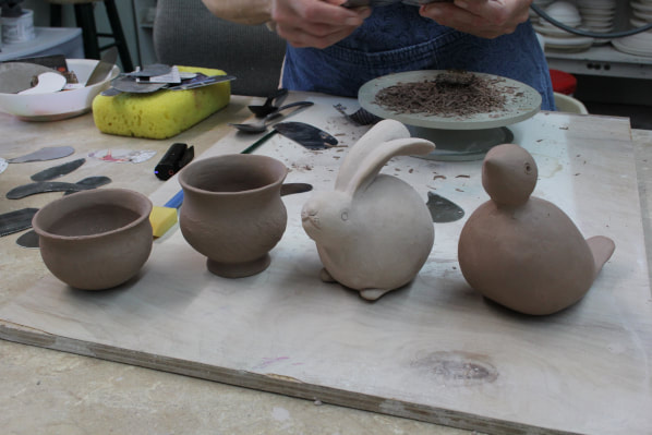 Antoinette teaches potters how to use pinched pots to make small clay animals.