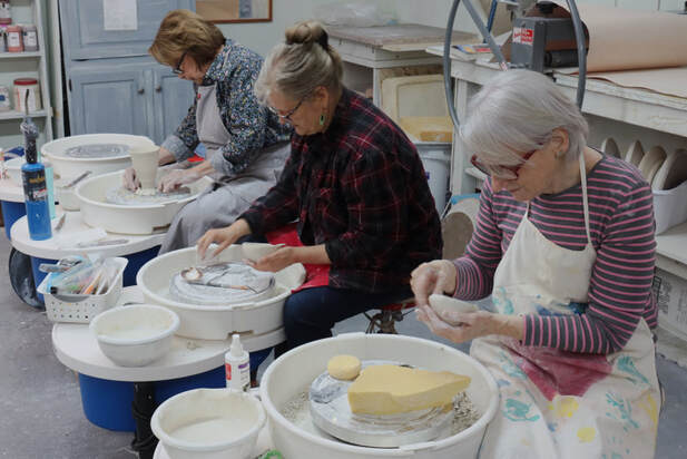 Participants work with porcelain at their pottery wheels during a small-group studio workshop. This is a time for individual exploration.