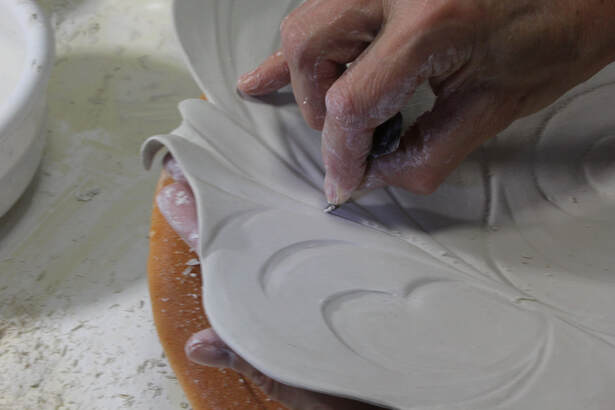 Antoinette shows how she altered the rim of a large, shallow bowl and how she carves into the clay and refine it.  