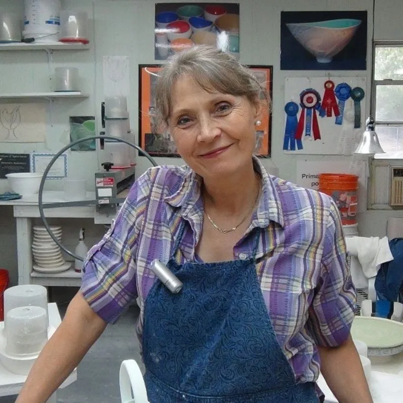 Antoinette Badenhorst in her pottery studio during the recording of her online porcelain class, "Understanding Porcelain". Her show rewards and a picture of one her translucent porcelain bowls are visible in the background of the image.