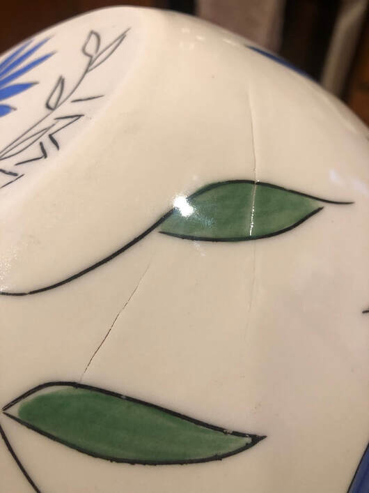 Spiral cracks showing on this white bowl with leaflike decoration. 