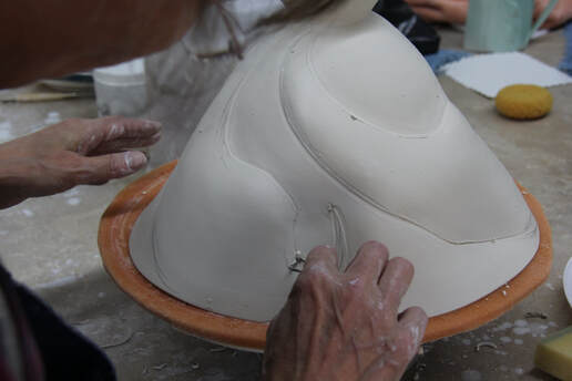 Antoinette is showing an altered porcelain pot and how she begin the first outlining, before carving the detail. 