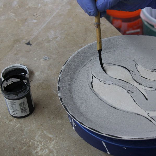 Spray painting can be combined with brush-on painting techniques. Antoinette teaches potters how she uses different glazes and under glazes to decorate a porcelain plate that she thrown on the wheel in her pottery studio in Saltillo Mississippi. 