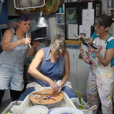 Antoinette Badenhorst demonstrating how to alter a porcelain form while workshop participants watch.