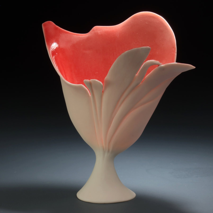 A translucent press molded porcelain sculpture in the shape of wavy leaves in the wind. The inside of the porcelain vessel is red with a soft white of the porcelain clay on the outside. The sculpture is resting on a white handmade porcelain foot. The background is black at the top that moves into a gray bottom that reflects the shades from the light above. Antoinette Badenhorst handbuilt this ceramic art piece. 