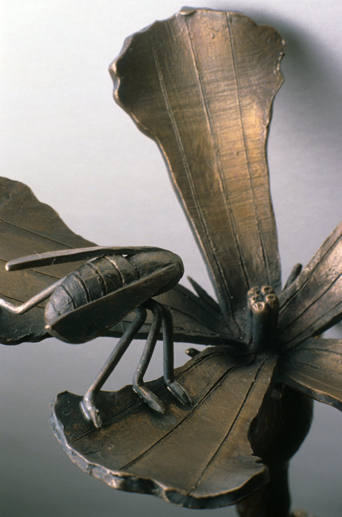 bronze sculpture of insect and plant