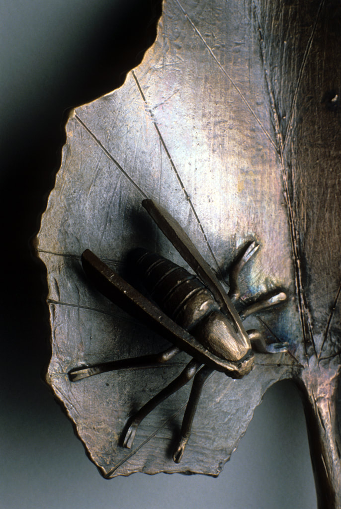 bronze sculpture of insect and plant