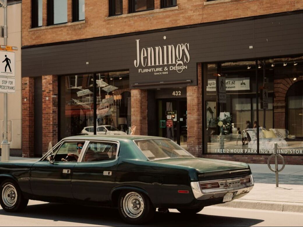 a vintage car is driving in front of a furniture store