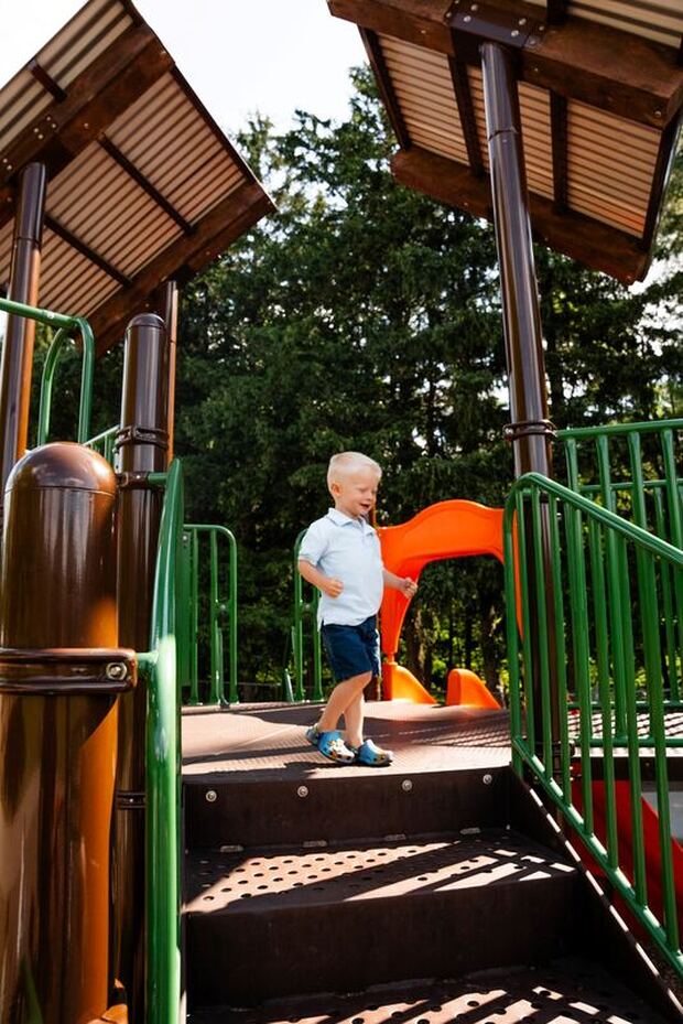 Here are two girls running in the playground of Pinafore Park. The one girl is wearing a colourful skirt, with navy blue leggings and a white top. The other girl is wearing a navy blue and red patterned dressed. they are running towards the rock climbing station of the park.