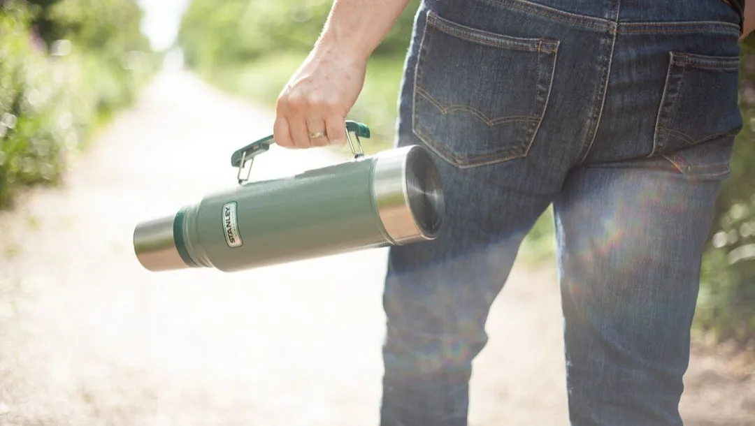 a person carries a Stanley Thermos of tea down the path towards the St. Thomas Elevated Park