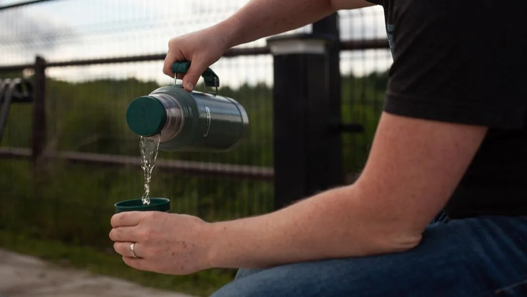 A person pours tea from a Stanley Thermos while sitting at the St. Thomas Elevated park