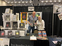 Elle and husband standing together behind book booth table 