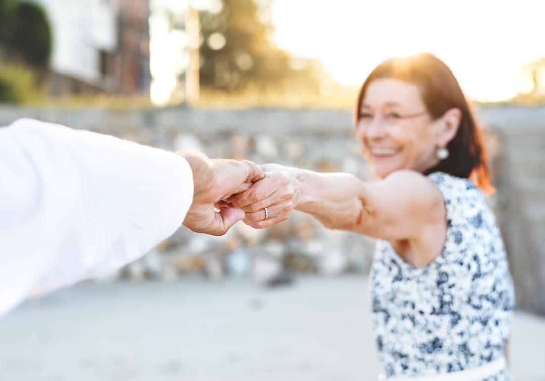 older woman holding hands with man