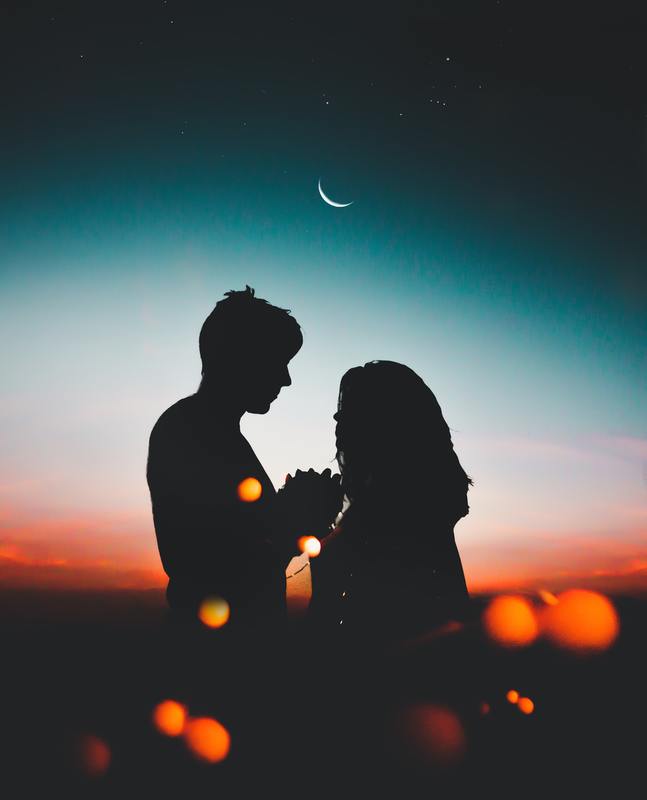 man and woman holding hands sunset