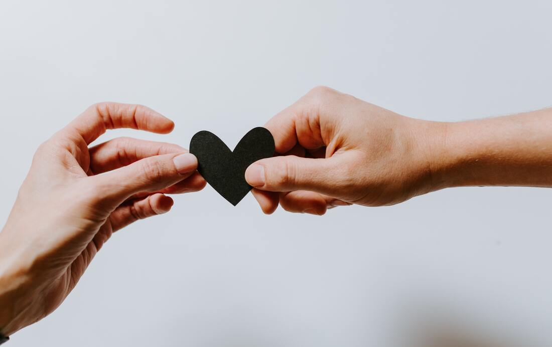 man and woman holding paper heart