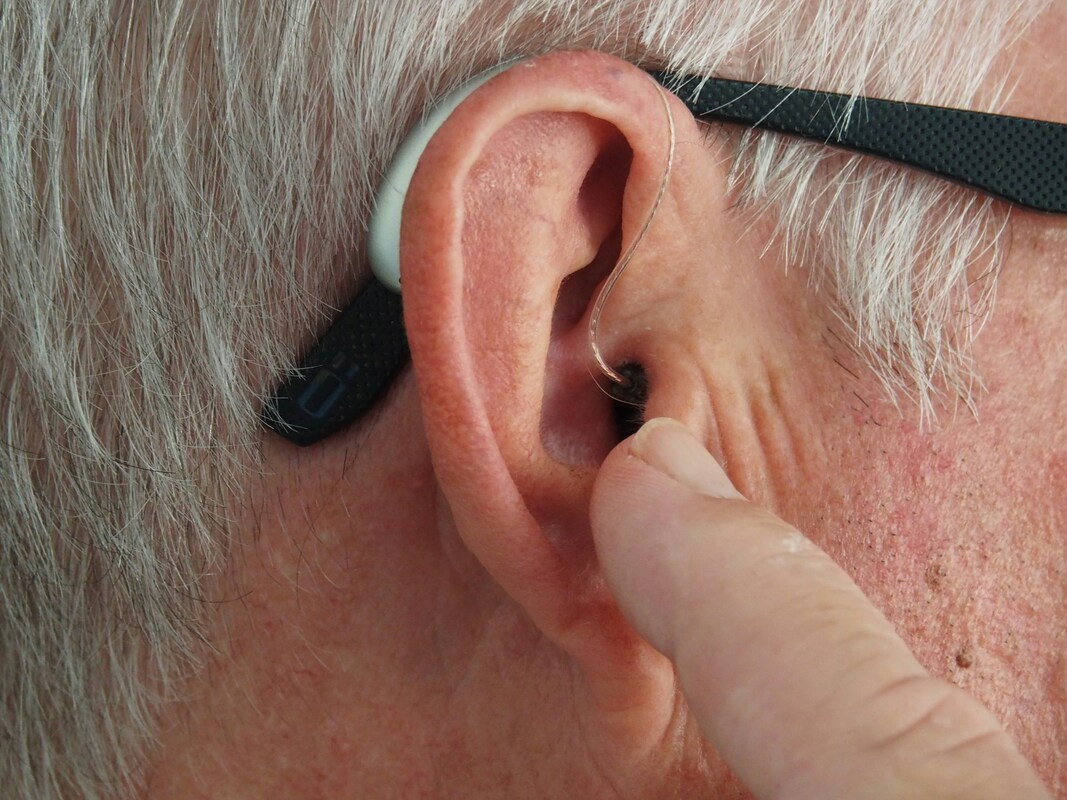man pointing to his hearing aid in his ear