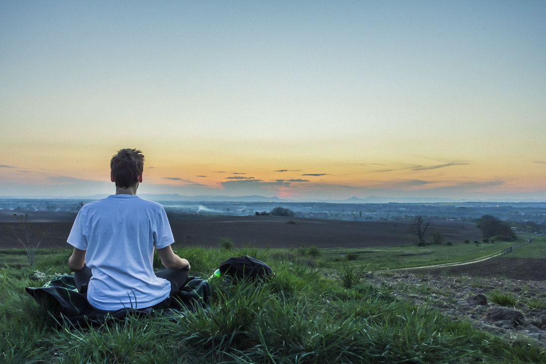 man meditating to sunset