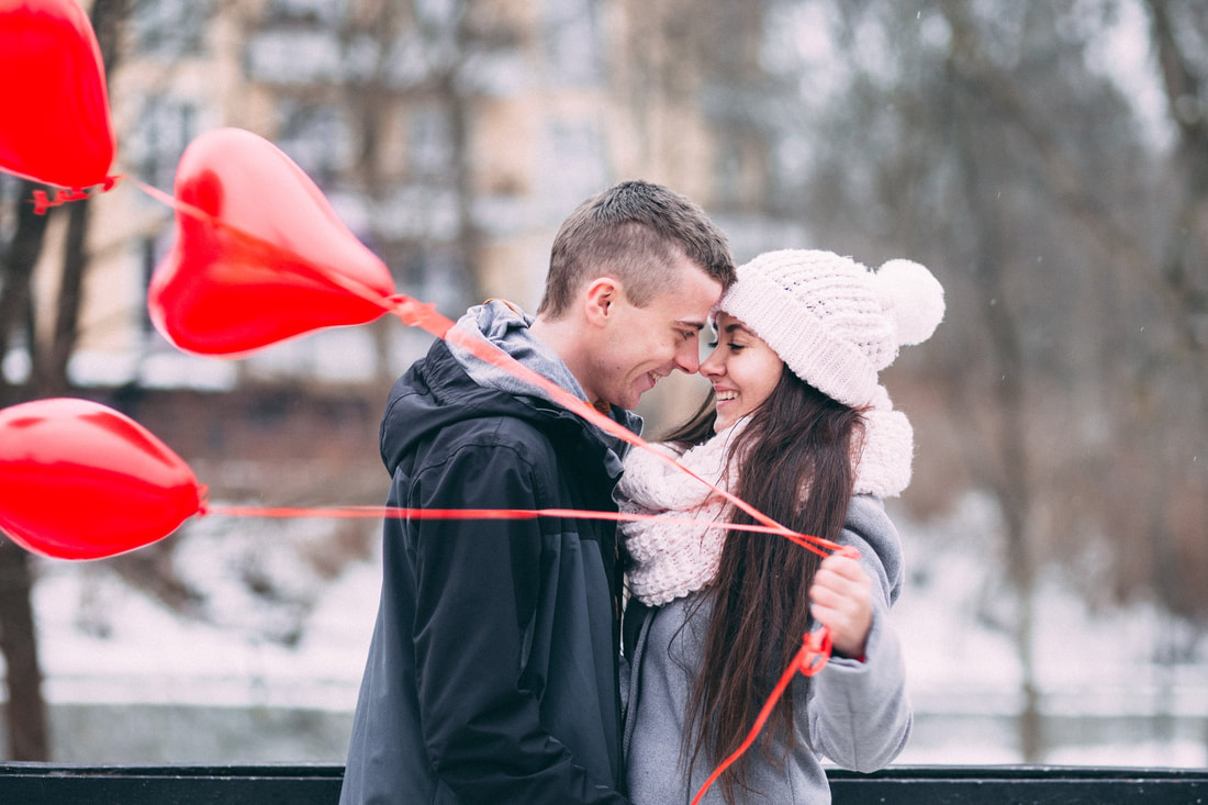 man and woman holding heart balloons