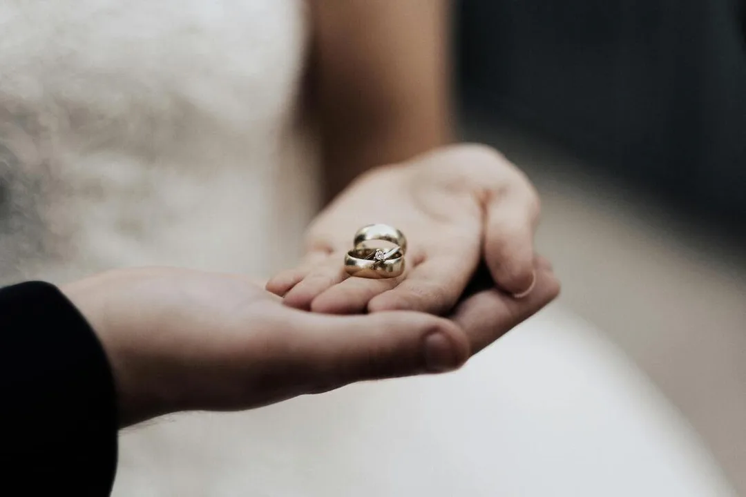 A couples hands holding their wedding rings