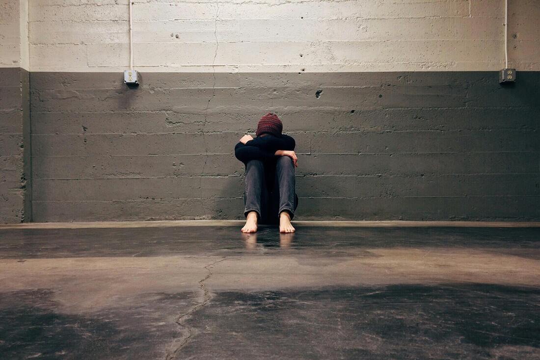 Person Leaning on wall head in hands