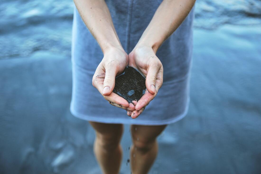 woman standing in water holding hands out