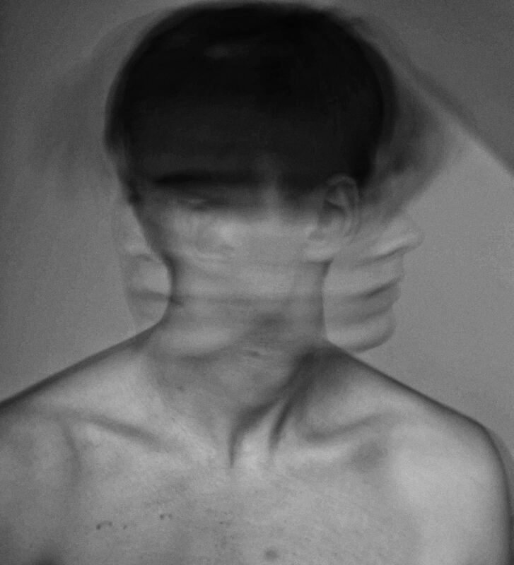 A black and white photo of a young man shaking this head. This represents the feelings associated with chlidhood trauma. Sacred Circle Holistic Healing offer online therapy in Kansas for childhood trauma, anxiety, and low self-worth.
