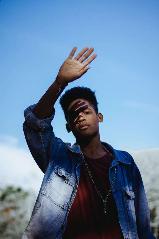 Young black man with his hand in front of his face. This represents clients that come for counseling and therapy for childhood trauma in Lawrence, Kansas.