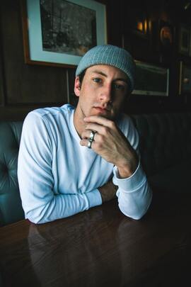 Young man wearing a beanie and looking into the camera with his hand on his chin. This represents that Sacred Circle Holistic Healing offers online therapy in Kansas for highly sensitive people struggling with anxiety, low self-esteem, and codependency.
