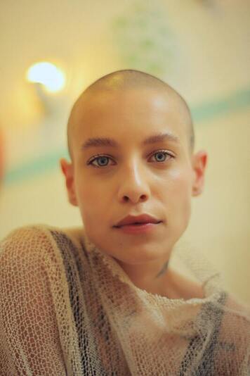 portrait of a young white woman with a shaved head and blue eyes, staring into the camera. This represents that Sacred Circle Holistic Healing offers individual therapy in Kansas for Highly Sensitive adults.