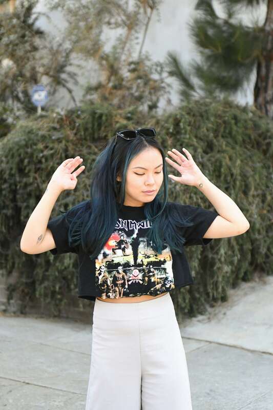 Young woman with green hair lookiing down with her hands up in the air. The illustrates the young adults who come to therapy to heal their childhood trauma.