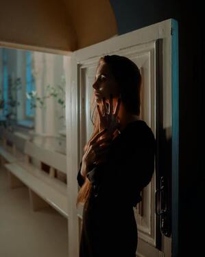 Silhouette of a woman standing in a doorway in evening light. This illustrates that nature of grief and that Sacred Circle Holistic Healing offers online grief and bereavement counseling in Kansas. 