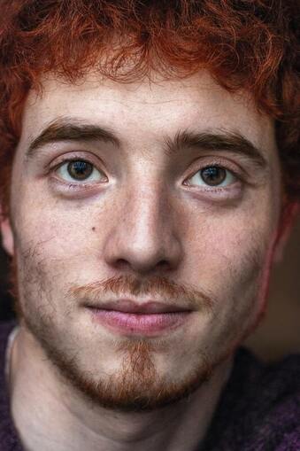 Close up portrait of a young man with red hair and red goatie, smiling at the camera. This represents that Sacred Circle Holistic Healing offers online therapy in Kansas, helping people develop self-compassion and healing past trauma.