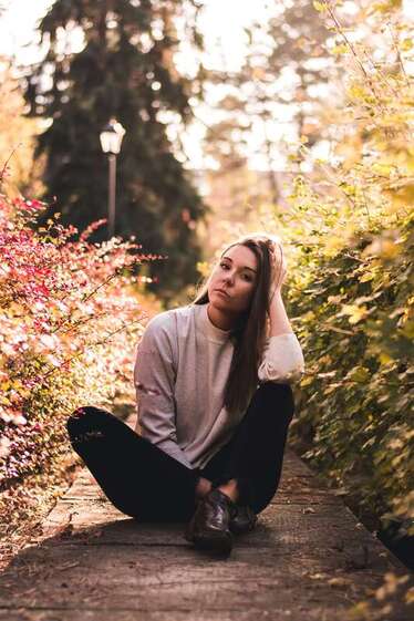 Young woman sitting on a path looking at the camera representing clients who have come to Sacred Circle Holistic Healing in Kansas for online therapy for childhood trauma.