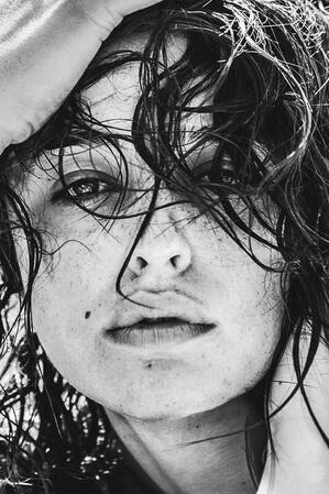 Black and white photo of nonbinary person who looks sad and is running their fingers through their hair. This represents that Sacred Circle Holistic Healing in Kansas provide therapy for anxiety.