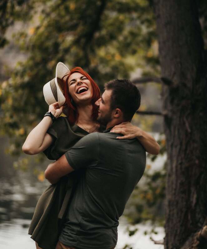 Young man and woman hugging and laughing representing young adults who have come to therapy in Kansas for childhood trauma, anxiety, and self-esteem. 