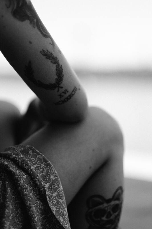 Black and white photo of a side of a woman's body, sitting down. This represent how grief is an embodied experience. Maggie Jones Boyle is a therapist, evolutionary astrologer, and grief educator based out of Lawrence, Kansas.