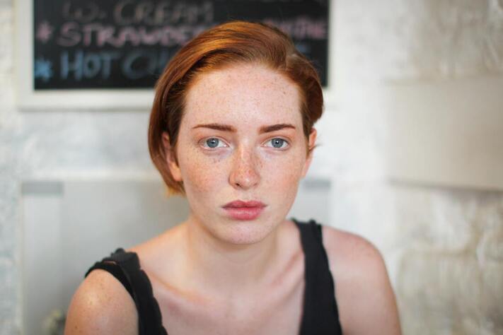 A young woman with red hair, staring into the camera. This illustrates that Sacred Circle Holistic Healing offers online therapy for codependency to young adults in Kansas.