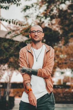 portrait of a young man in an orange hoody smiling at the camera. This illustrates the Sacred Circle Holistic Healing offers online therapy for adults in Kansas.