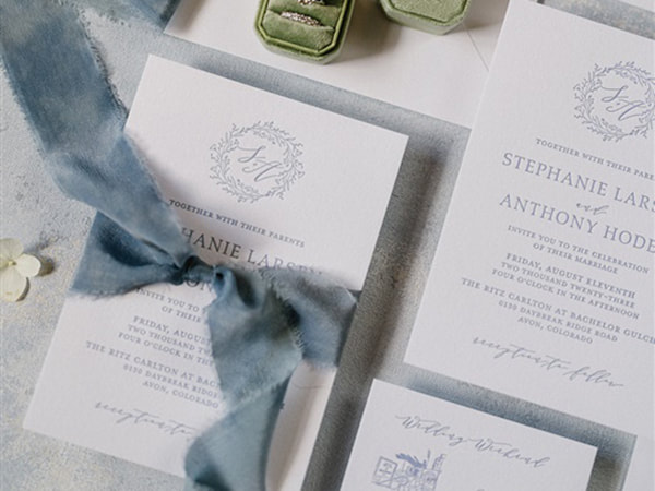 Slate blue and white letterpress invitation suite, with monogram wreath at top, classic text, tied with blue silk ribbon
