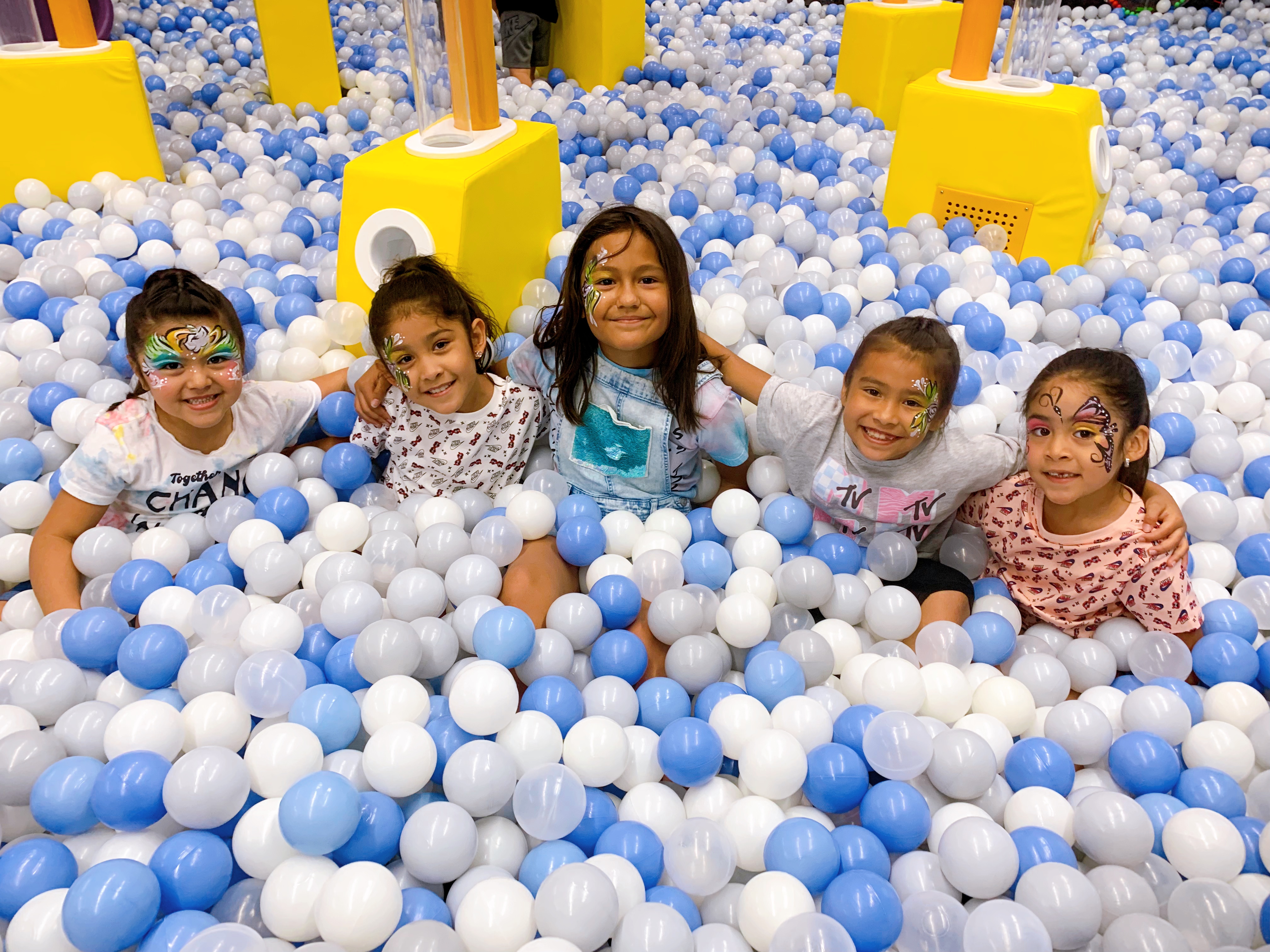 Children smiling together in the ball pit at Smarty Sprouts Kids’ Club.