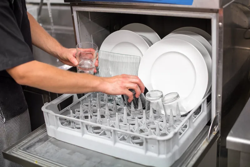 Unloading commercial dishwasher.