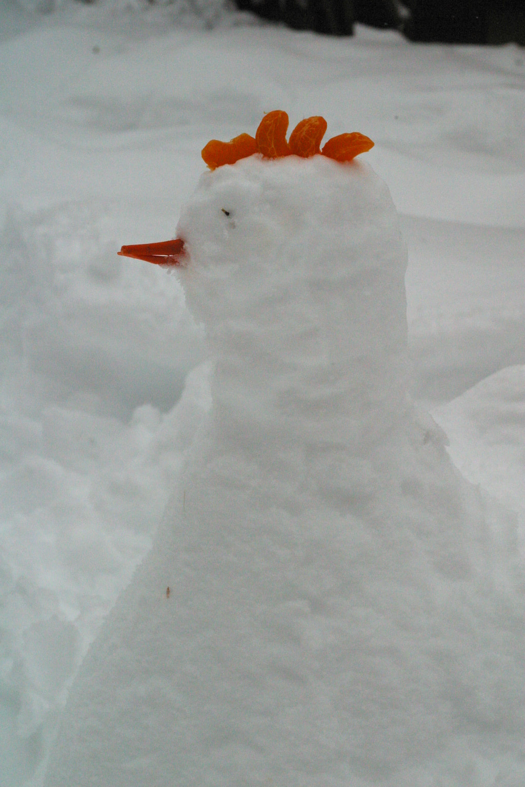 A chicken made of snow with a carrot for a beak.