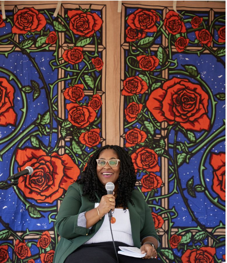 Dr. LaNysha Adams smiling on stage in front of a rose-patterned backdrop