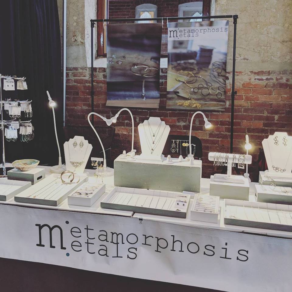 a table of jewelry displayed at a craft show