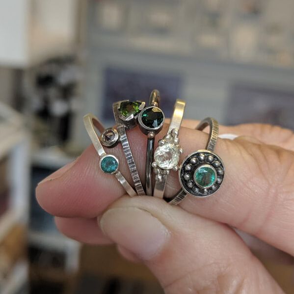 a hand holding 5 rings with gemstones