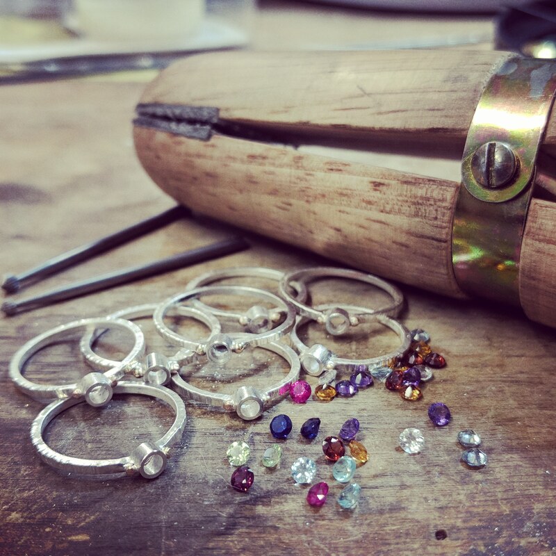 empty ring settings with loose colored stones and tools