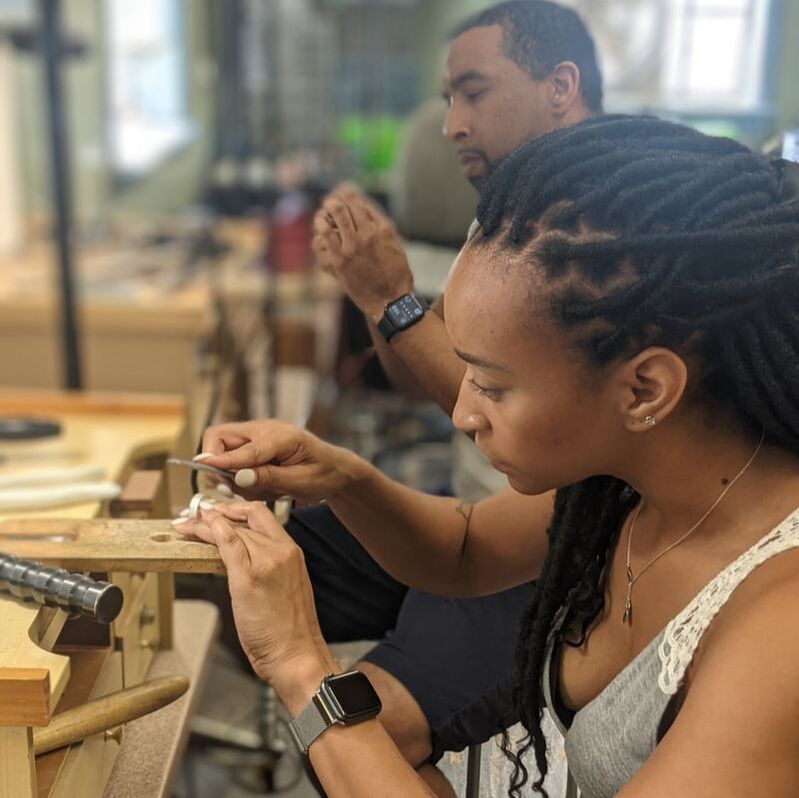 A man and woman making their wedding bands in a workshop
