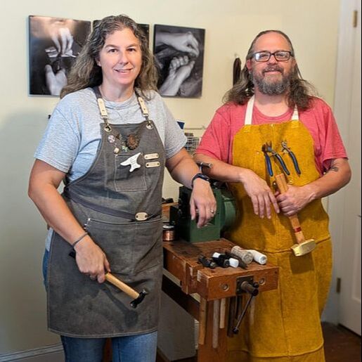 A man and woman holding tools standing beside a workbench