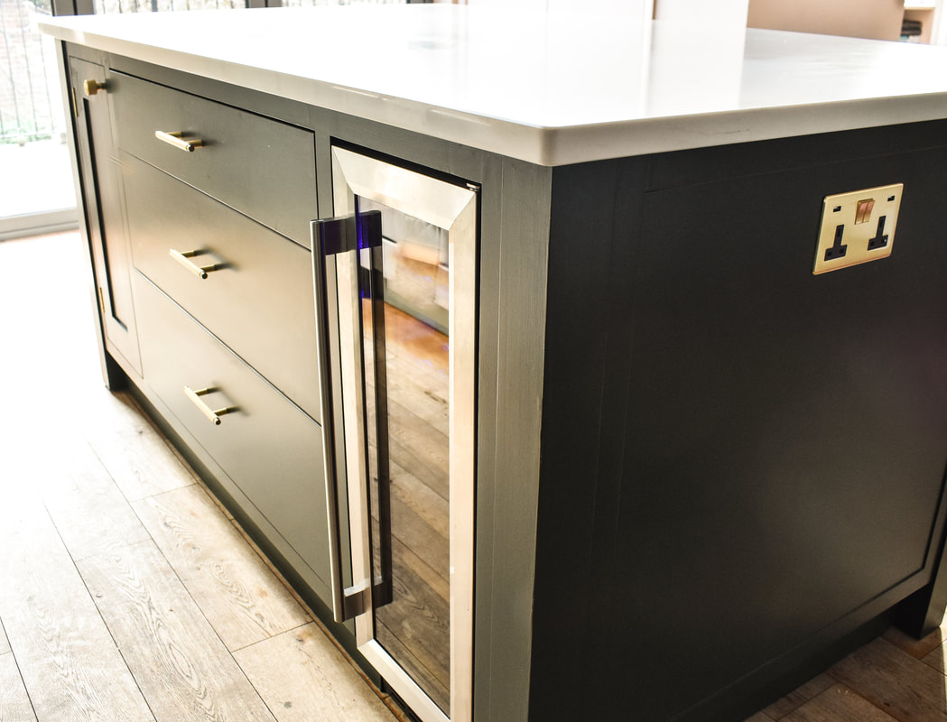 An elegant handmade bespoke kitchen island with panelled doors an integrated  wine fridge, drawers, designed made and fitted in Highgate North London